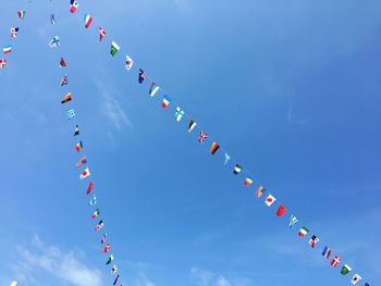 Low angle view of various flags hanging against sky