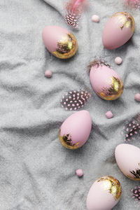 Easter eggs are painted with gold and violet paint on a gray linen background. 
