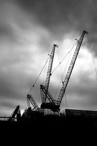 Low angle view of cranes at construction site against sky