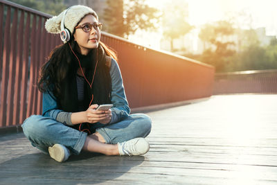 Close-up of young woman listening to music on footpath