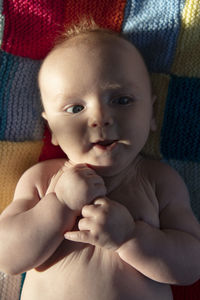 Portrait of cute baby boy lying on bed at home