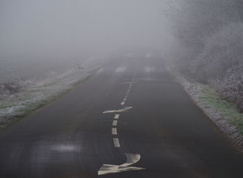 Road amidst landscape against sky during foggy weather