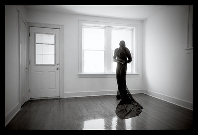 Side view of senior woman standing against door