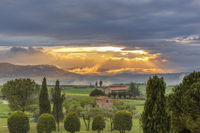 Houses on land against sky during sunset