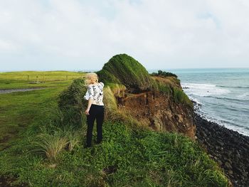 Rear view of woman on shore by sea against sky