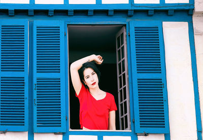 Portrait of young woman standing against building