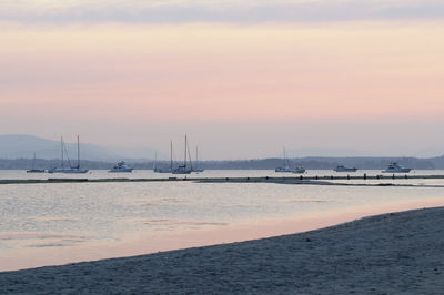 Sailboats on sea against sky during sunset