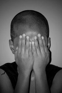 Close-up of boy covering face with hands