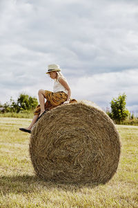 Girl sitting on bale of hay