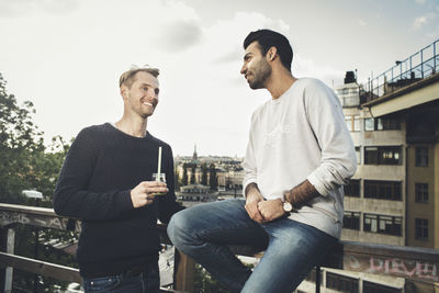 Happy male friends communicating on roof garden