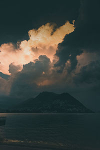 Scenic view of lake against cloudy sky during sunset