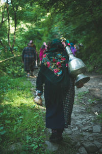 Rear view of people wearing traditional clothing while walking in forest