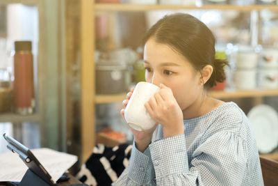 Portrait of young woman drinking drink in cafe