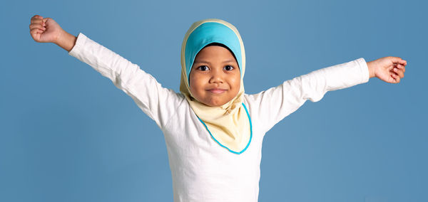 Portrait of smiling young woman standing against blue sky