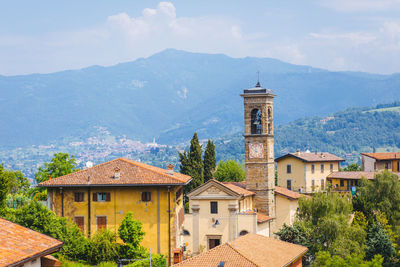 Houses by buildings against sky