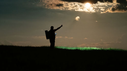 Silhouette man standing on field against sky during sunset