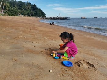 Rear view of girl on beach against sky