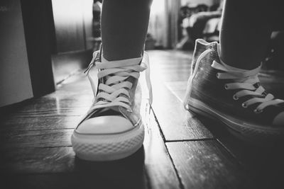 Low section of man wearing shoes standing on floor at home