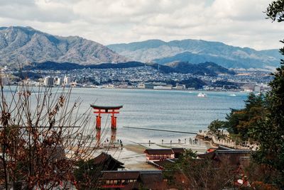 Torii gate in sea at itsukushima shrine against sky