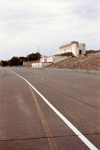 Empty road by buildings against sky