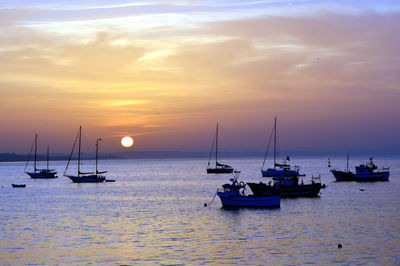 Sailboats in sea against sky during sunset