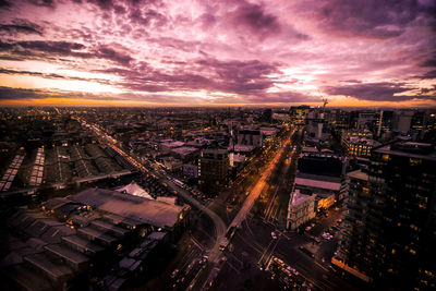 High angle view of illuminated cityscape against cloudy sky at dusk