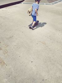 Rear view of boy skateboarding at playground during sunny day