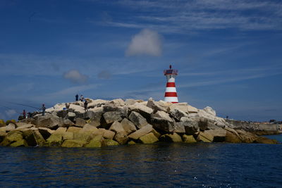 Lighthouse by sea against sky