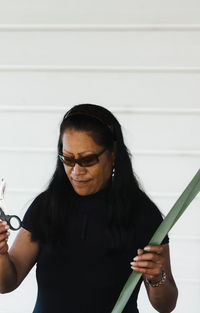 Young woman wearing sunglasses standing against wall