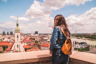 Woman standing by cityscape against sky