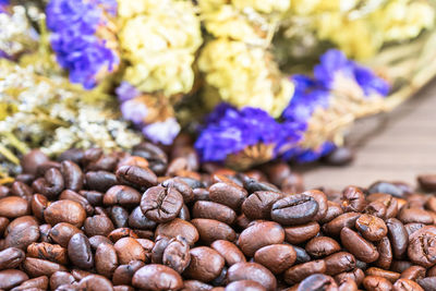 Close up roasted coffee beans heap with flower background