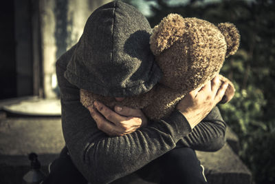 Man embracing teddy bear outdoors