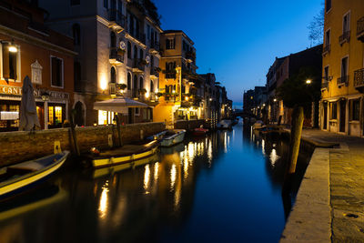 Canal amidst illuminated buildings in city at night