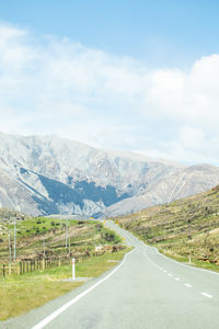 Road by mountains against sky