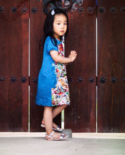 Portrait of smiling girl standing against door