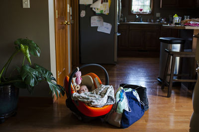 High angle view of new born resting in baby seat by luggage at home