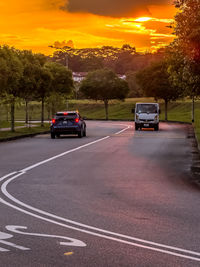 Cars on road against sky during sunset