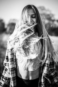 Smiling woman with tousled hair standing outdoors