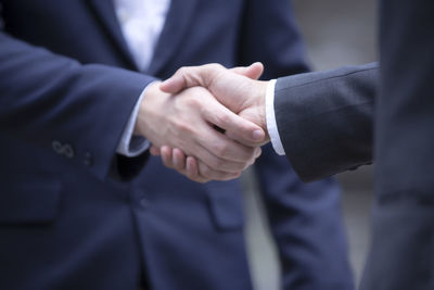 Midsection of businessman shaking hand with colleague