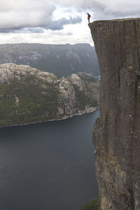 Hiker standing on edge of majestic pulpit rock cliff by lysefjorden fjord, norway