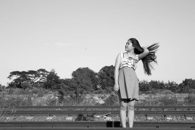 Woman standing by railing against clear sky