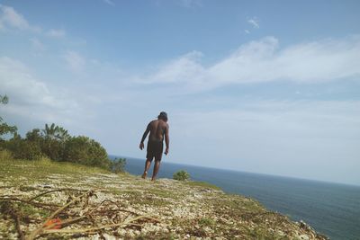 Rear view of man standing on sea against sky