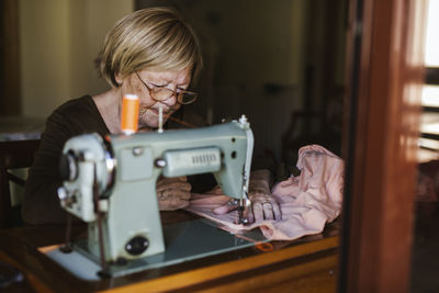 Senior woman using an sewing old machine at home