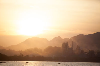 Scenic view of sea and silhouette mountains against sky during sunset