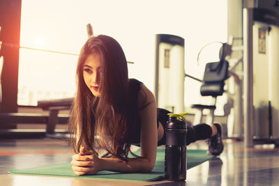 Young woman with long hair doing push-ups in gym