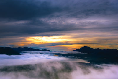 Scenic view of dramatic sky over silhouette mountains during sunset