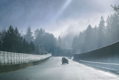 Road amidst trees against sky during winter