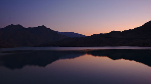 Scenic view of lake and mountains against sky during sunset