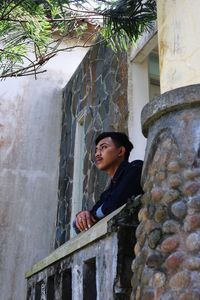 Low angle portrait of young man standing against building