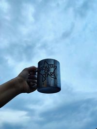 Low angle view of hand holding text against sky